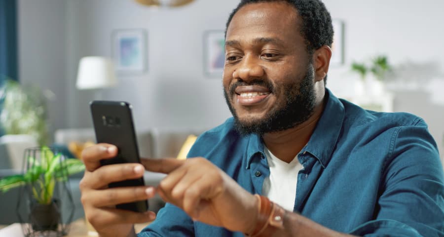 Man at home interacting with an app on his smartphone